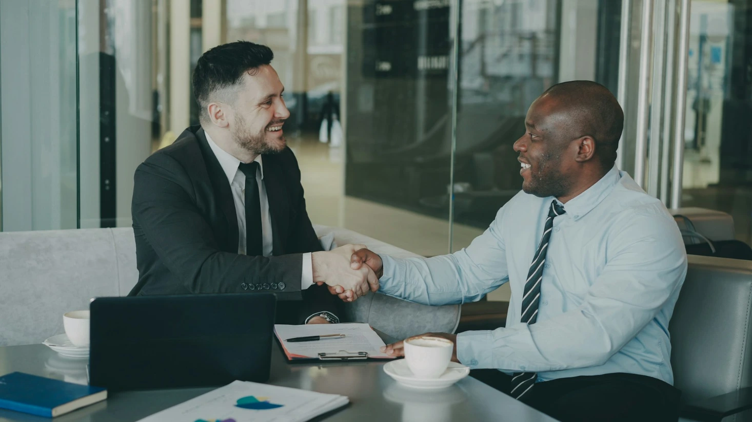 Two businessmen shaking hands across a table